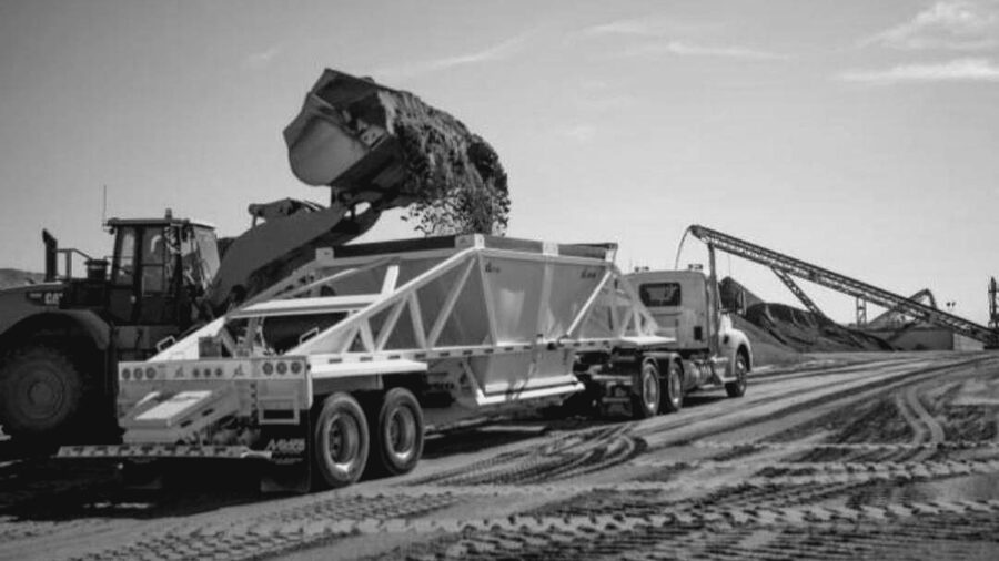 Wheel loader charging a belly dump trailer with aggregate at the pit